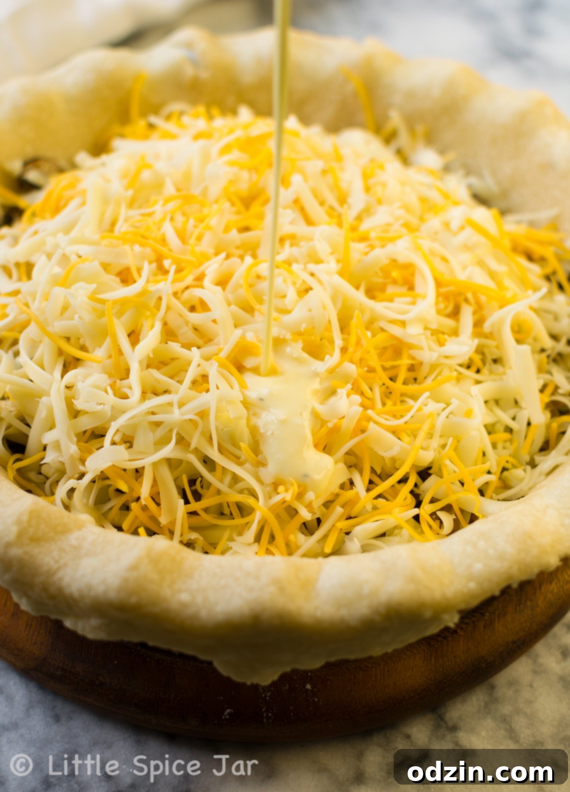 Ultimate Cheesy Spinach Mushroom Quiche 1 pouring egg mixture for quiche over cheese