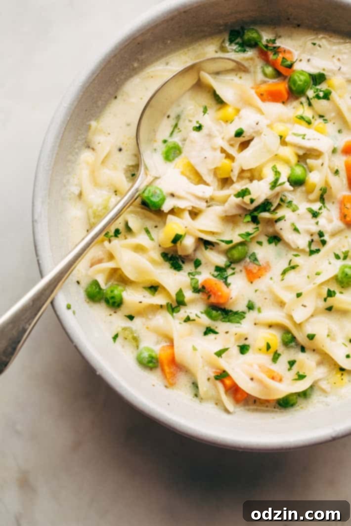 Serving Creamy Chicken Pot Pie Soup Bowl of Creamy Chicken Pot Pie Soup with Fresh Herbs - A close-up of a steaming bowl of homemade chicken pot pie soup, garnished with fresh parsley, ready to be enjoyed as a warm and hearty meal. #comfortfood #chickennoodlesoup