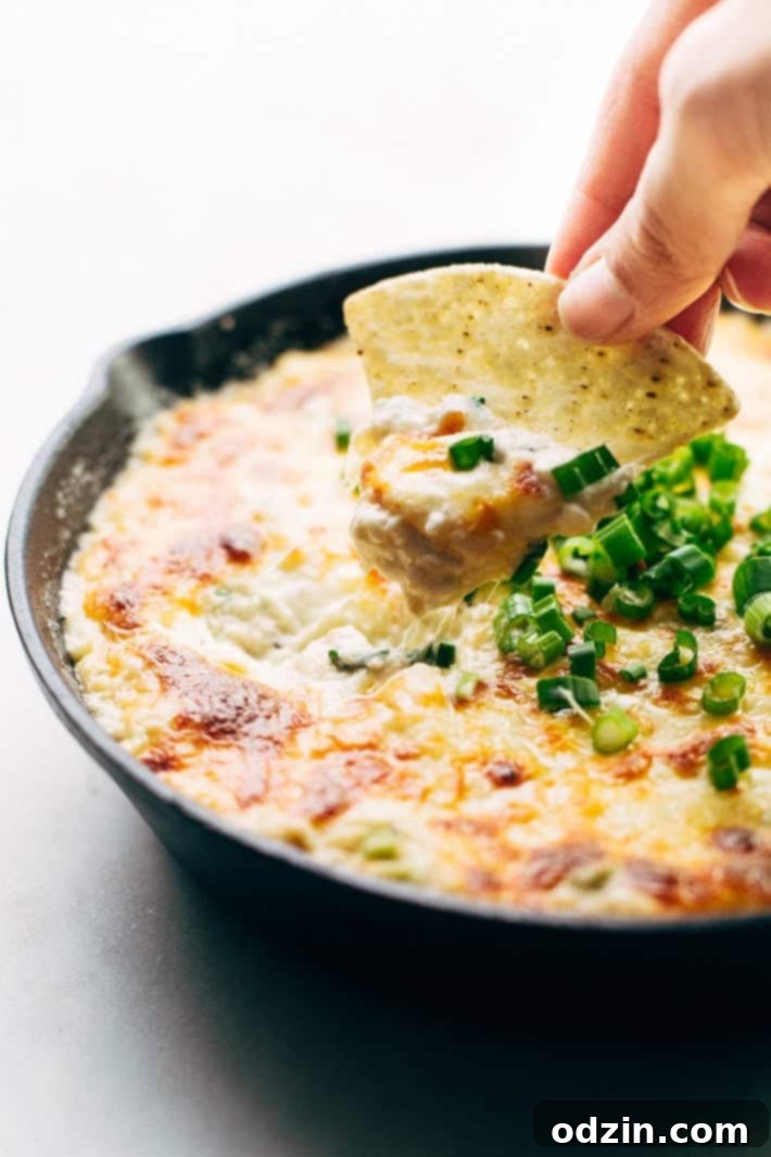 Hot Crab Dip with scallion garnish, served in a cast iron skillet