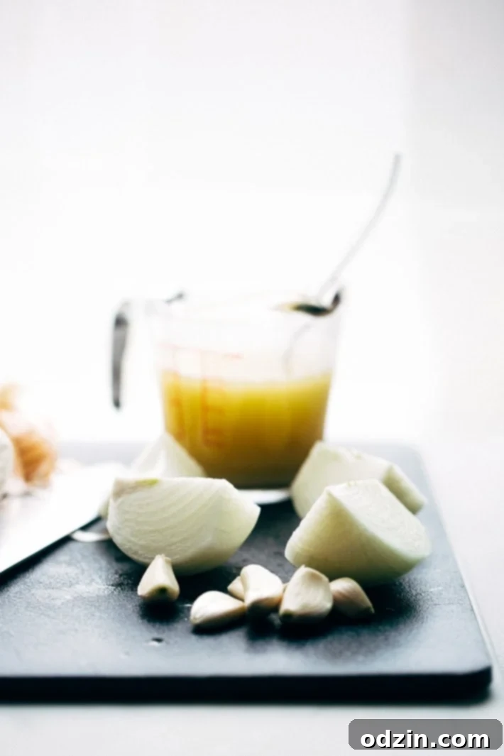 Pressure Cooker Crispy Chicken Carnitas - The easiest way to make carnitas! This instant pot recipe makes the most delicious carnitas! Top with lots of cilantro, onions, sautéed cabbage, and homemade chipotle sauce! #instantpot #carnitas #chickencarnitas #pressurecooker | Littlespicejar.com onions, garlic and broth on cutting board