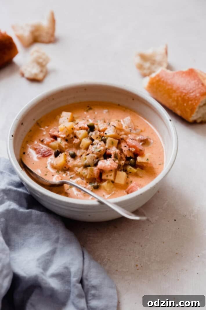 bowl of prepared smoked salmon chowder with blue linen towel and broken baguette pieces