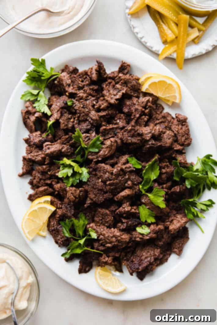 Cooked beef shawarma meat in a skillet, garnished with fresh parsley