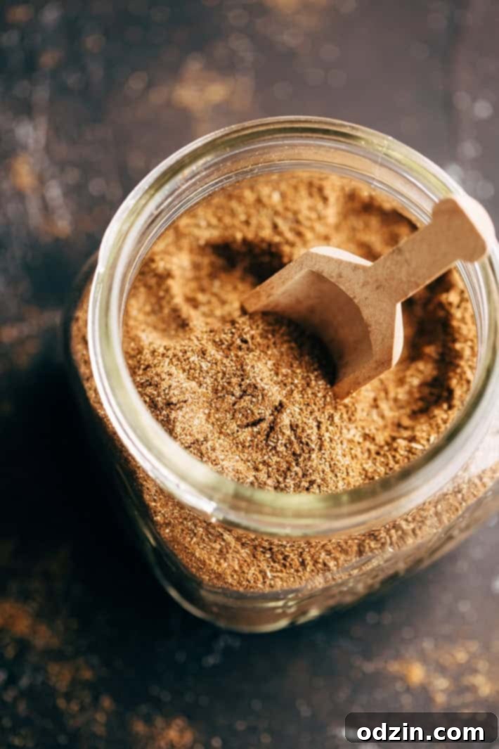 Close-up of homemade shawarma seasoning in a glass jar with a wooden spoon