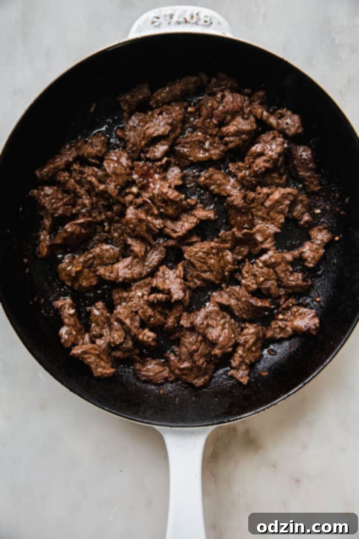 Cooked shawarma meat sizzling in a cast iron skillet