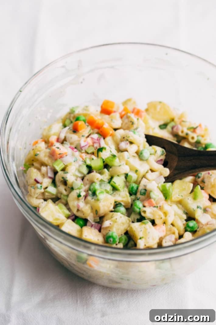 A large serving bowl filled with Macaroni Potato Salad, garnished with fresh parsley. Ready for a summer feast. #potatosalad #salad #macaronisalad #picnic #barbecue #familyrecipe