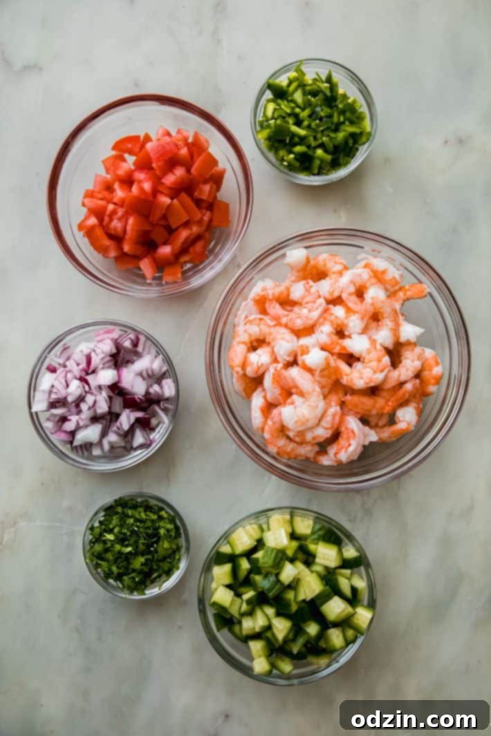 Close-up of fresh, vibrant ingredients for Mexican shrimp cocktail displayed on a marble surface.