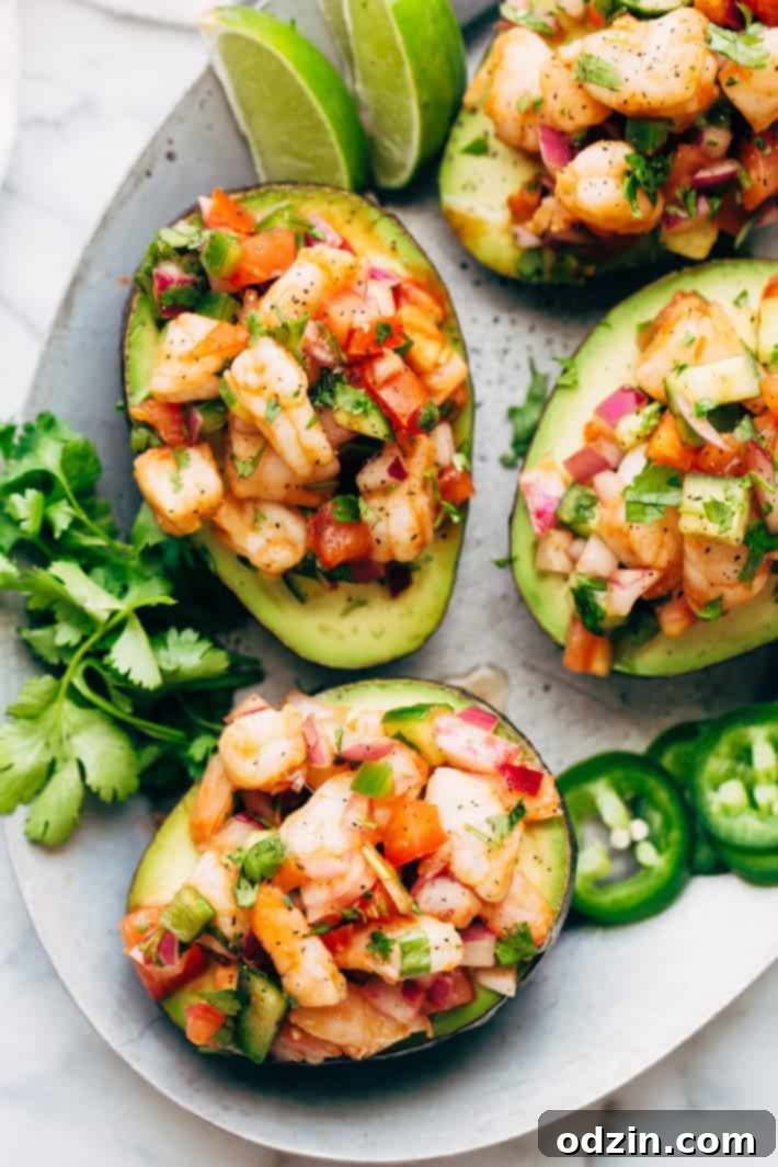 Mexican shrimp cocktail, Coctel de Camarones, meticulously stuffed into avocado halves and presented on a plate.