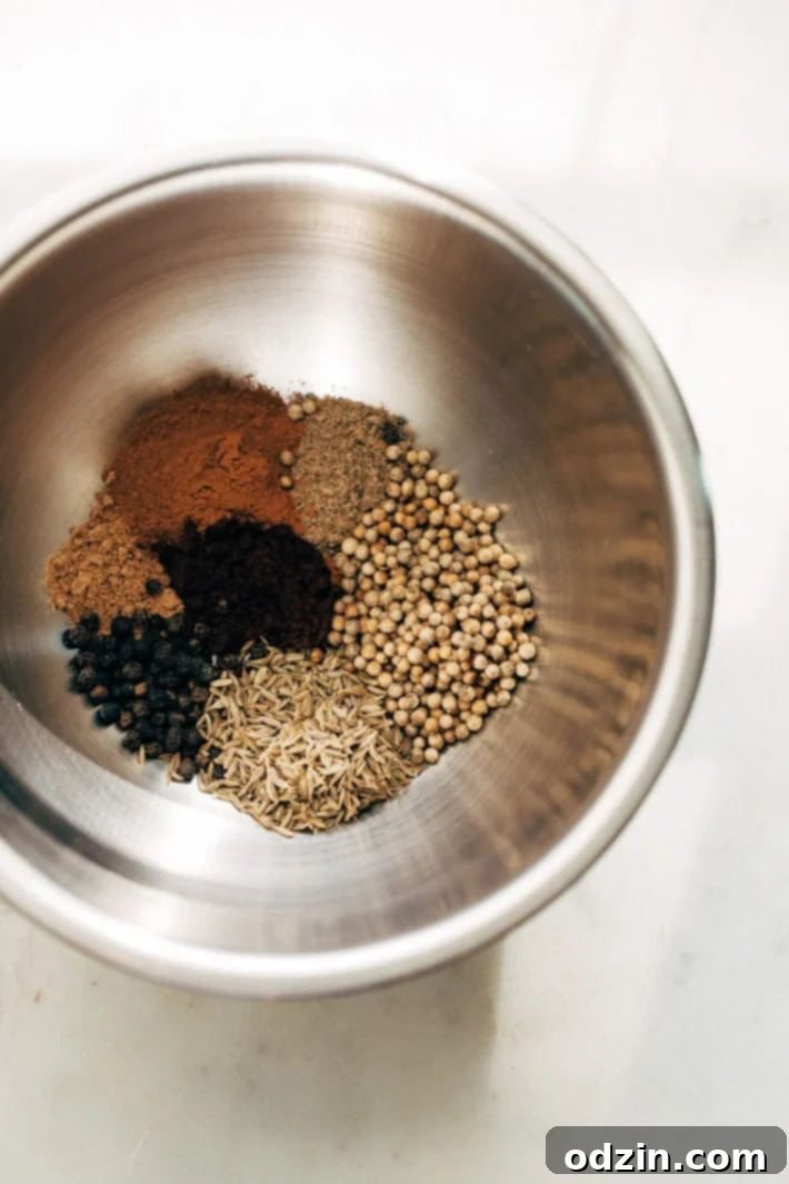 Homemade Thai Massaman Curry Paste - A quick 15 minute paste that's perfect to use in all kinds of curries! This can also be made vegan/vegetarian friendly. #massamancurry #homemadecurrypaste #thaicurry #massamancurrypaste | Littlespicejar.com Ingredients for homemade Thai Massaman curry paste laid out on a cutting board, including fresh ginger, garlic, shallots, and various spices.