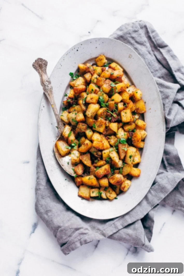 Oval metal plate with a spoon and perfectly cooked, golden brown skillet breakfast potatoes cut into small cubes