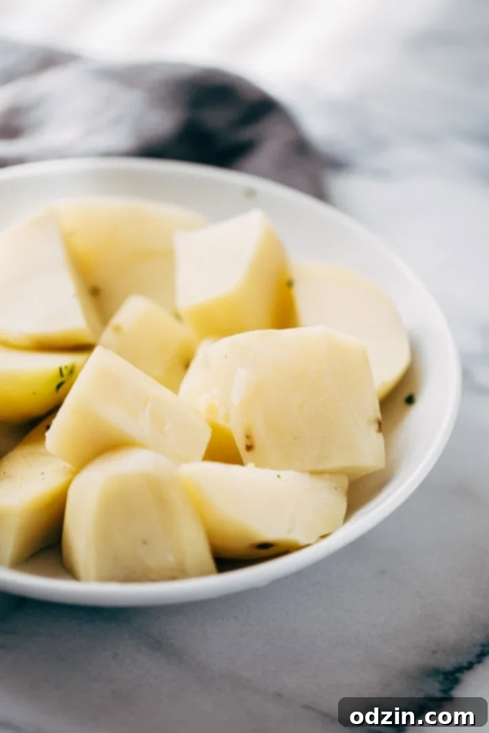 Perfectly steamed and diced potato cubes on a plate, ready to be seasoned and fried in a skillet