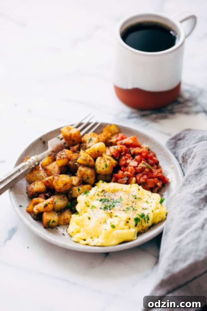 A complete breakfast scene featuring golden pan-fried breakfast potatoes, fluffy scrambled eggs, fresh salsa, and a cup of coffee on the side, ready to be enjoyed