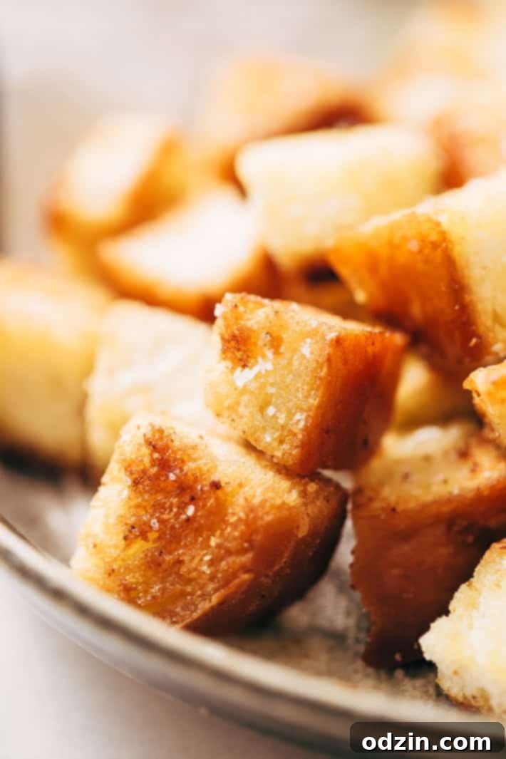 A close-up of a serving of Instant Pot Cajun Butternut Squash Soup, showing its smooth texture, vibrant color, and generous topping of garlic croutons.