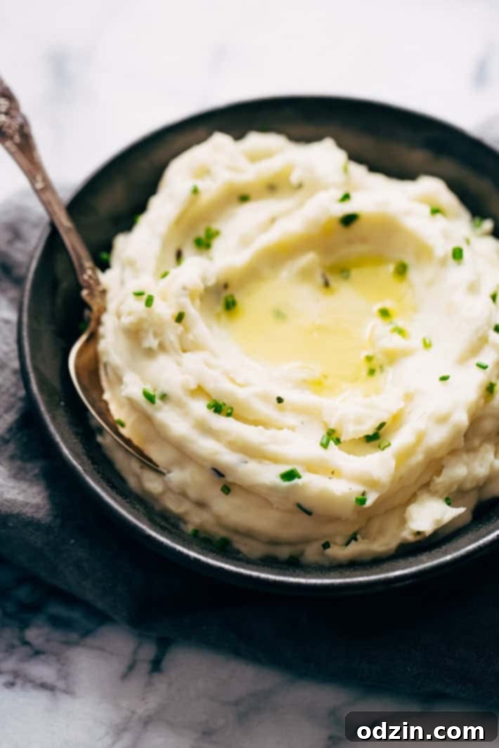 mashed potatoes topped with chives and melted butter in bowls with spoon