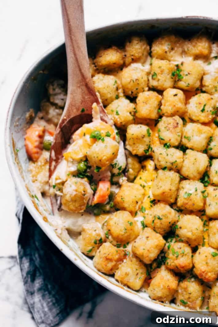Serving Chicken Pot Tater Tot Hotdish - A spoonful of the hearty casserole being dished out, showing the creamy filling, chicken, vegetables, and crispy tater tots.