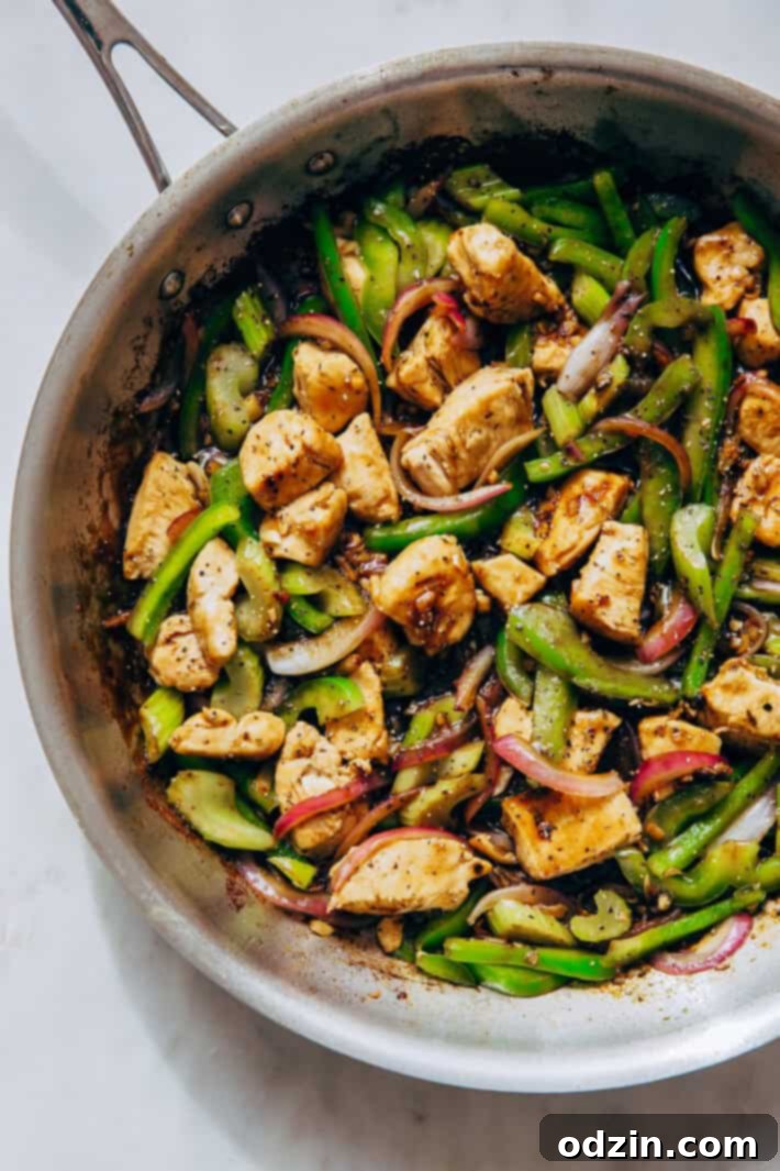 skillet with prepared pepper chicken stir fry on white marble
