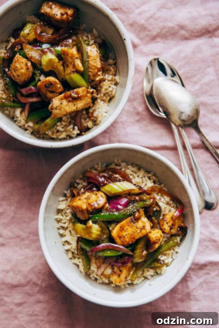 bowls of rice topped with chicken stir fry on mauve linen napkin with spoons