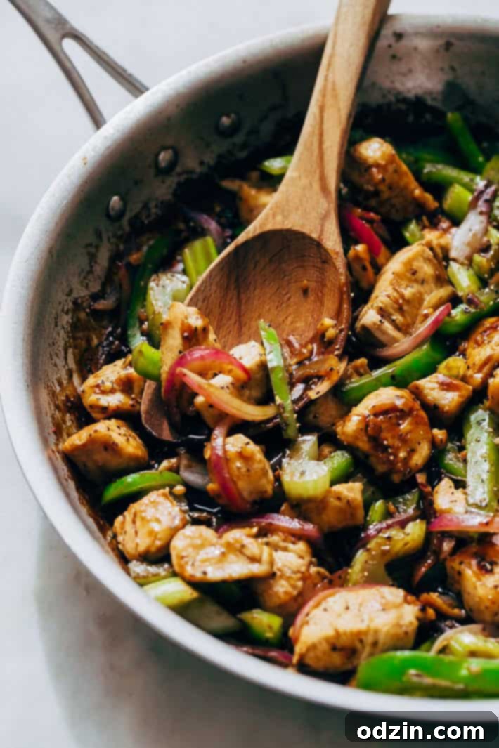 skillet with wooden spoon and prepared chicken stir fry with vegetables
