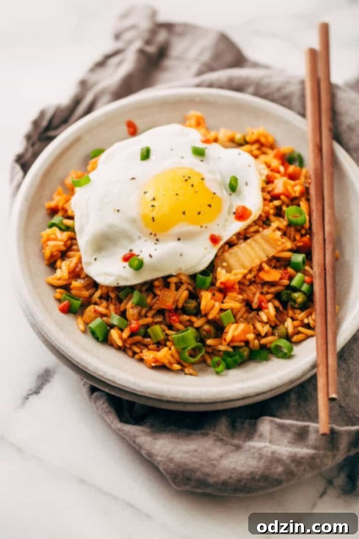 Delicious Kimchi Fried Rice with Fried Egg A vibrant bowl of kimchi fried rice, with a sunny-side-up egg and green onions, ready to eat.