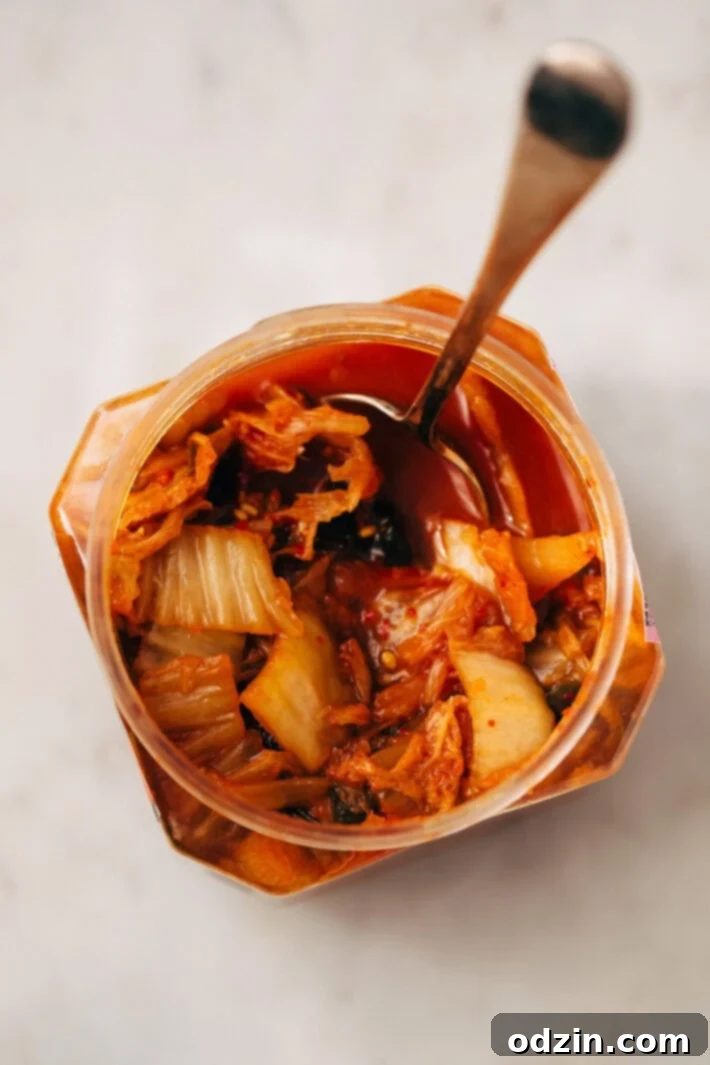 A glass jar filled with vibrant, fermented kimchi, ready to be served as a spicy and tangy side dish or topping.