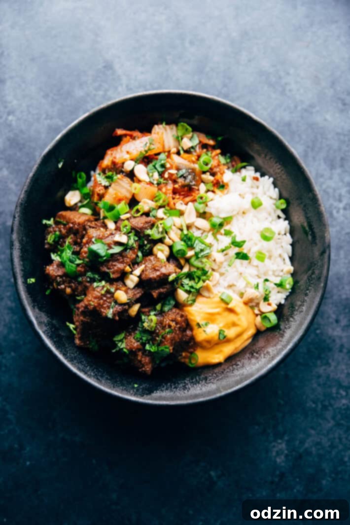 A close-up of a perfectly assembled Korean beef bowl, featuring tender beef, a bed of white rice, vibrant kimchi, and fresh garnishes, ready to be enjoyed.