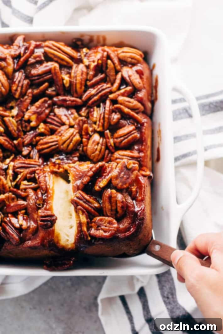 Unbaked sticky buns arranged in a caramel pecan lined baking dish