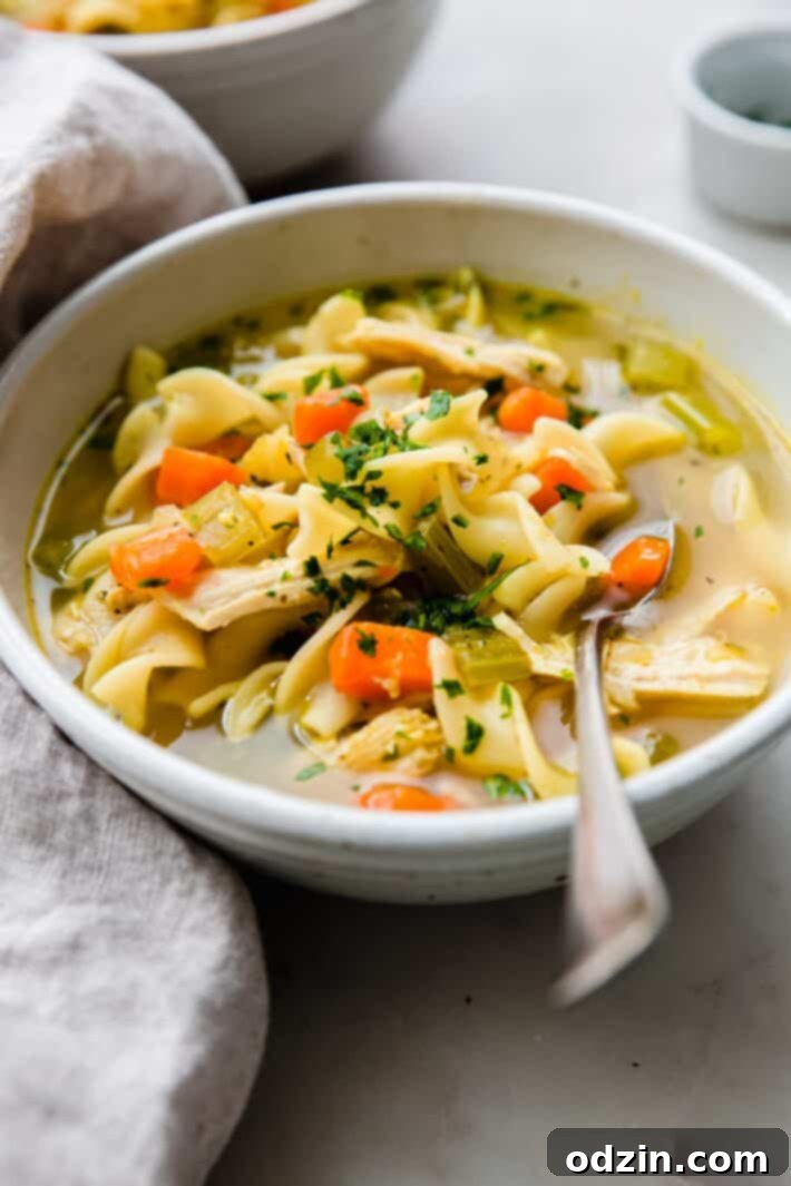 Warmth in a Bowl: Chicken Noodle Soup for Colds 6 bowl of soup on white marble with spoon and linen napkin