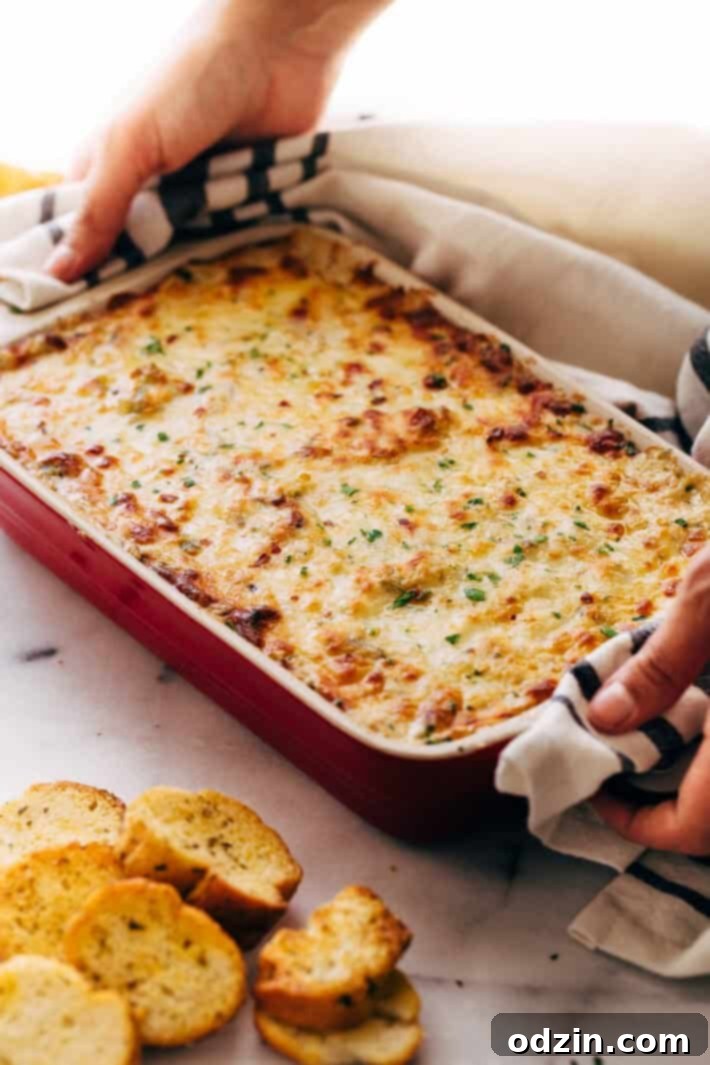 Serving Philly Cheese Steak Dip with crostini Philly Cheese Steak Dip being scooped with crostini, showing cheese pull
