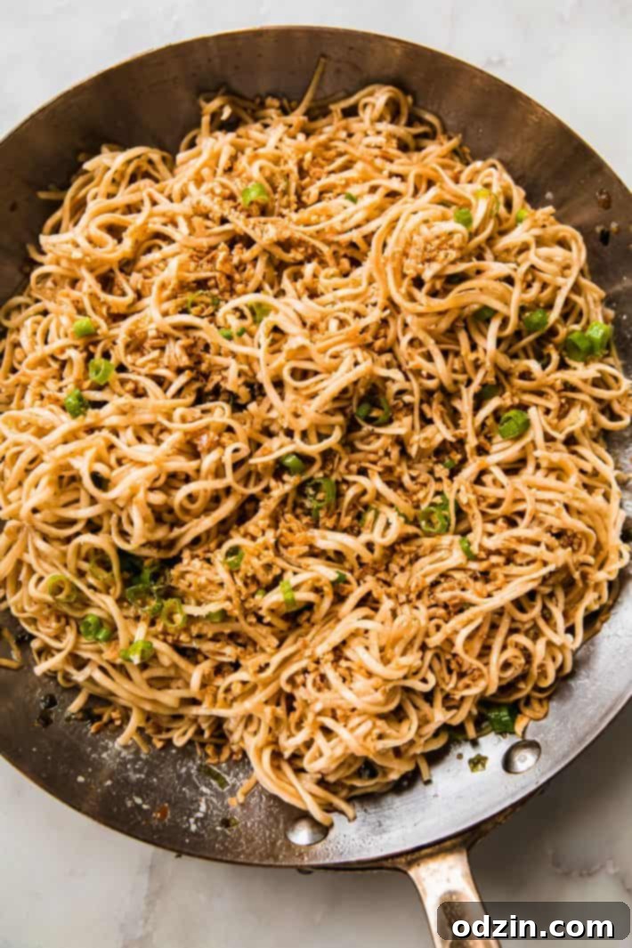 Close-up of a bowl of quick garlic noodles with green onions and fried garlic