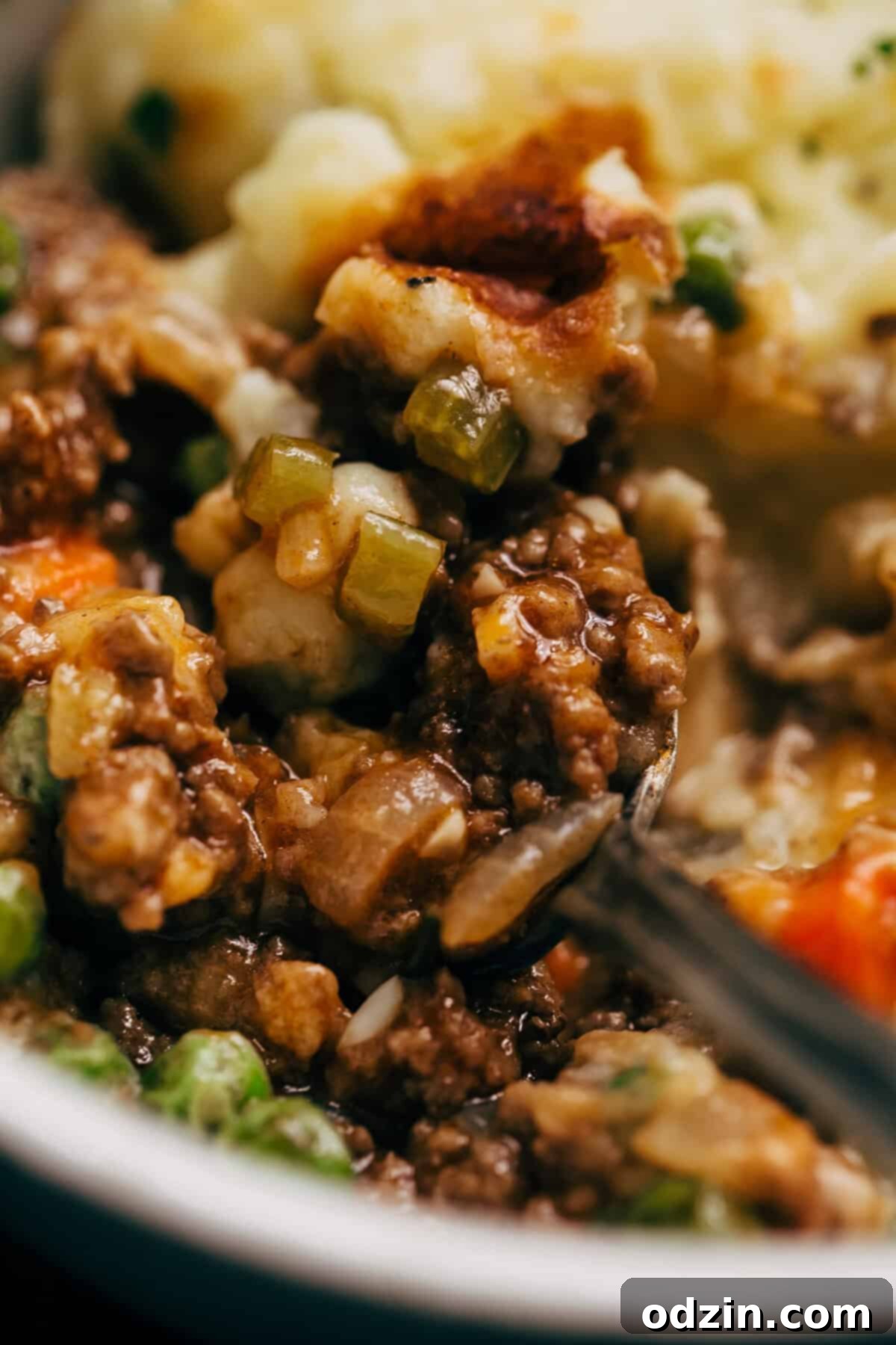 Close-up of shepherd's pie filling with rich meat and vegetables, topped with smooth mashed potatoes before baking