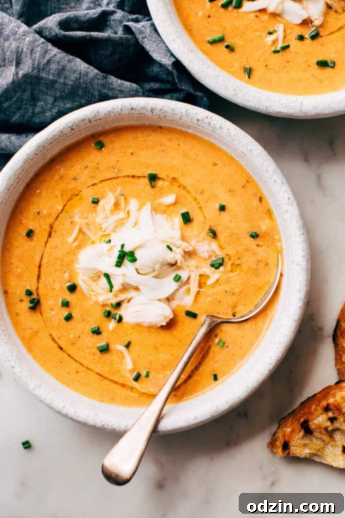 Blushing Tomato Crab Bisque, a creamy and spicy seafood soup made with sweet roasted tomatoes, carrots, onions, and garlic, combined with succulent jumbo lump crab meat. Perfect for any season. #crabbisque #tomatocrabbisque #roastedtomatosoup #seafoodbisque #creamysoup