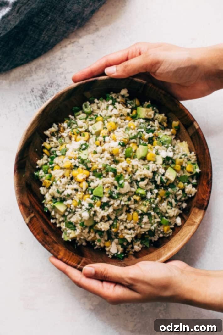 Delicious & Easy Street Corn Salad A bowl of freshly mixed Street Corn Rice Salad, glistening with dressing and topped with fresh cilantro. Ready to be served.