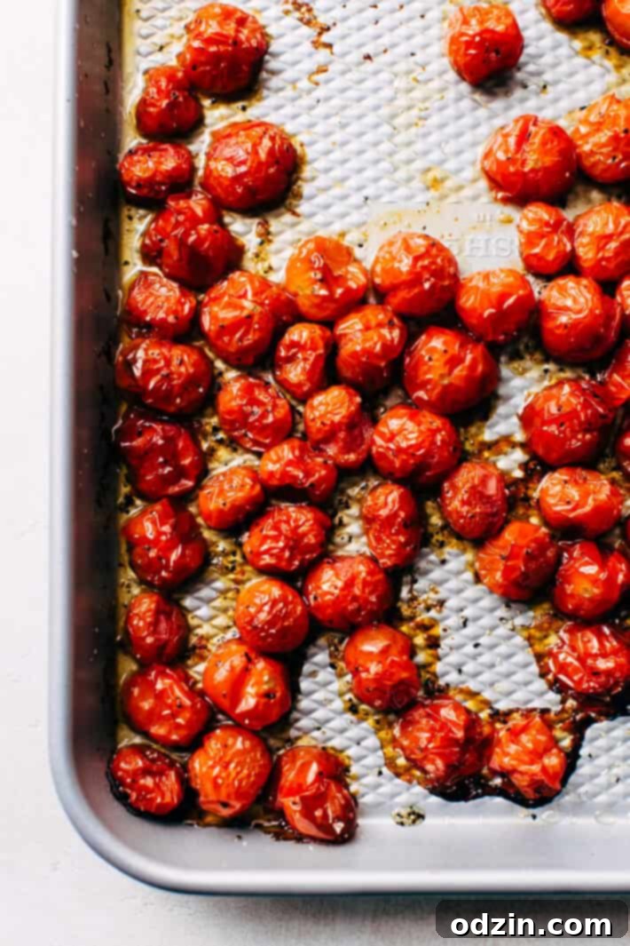 Roasted Garlic Italian Couscous Salad - made with homemade roasted garlic Italian dressing and tons of yummy salad toppings! Perfect for potlucks or picnics! #couscoussalad #italiansalad #salad #picnic #potluck #italiansalad | Littlespicejar.com Close-up of roasted cherry tomatoes on a baking sheet, glistening with olive oil