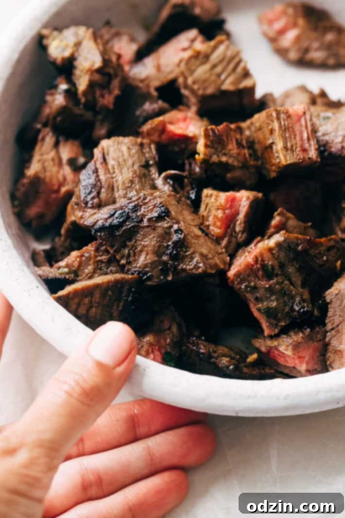 Several Mojo Steak Tacos topped with guacamole, onions, and cilantro on a platter