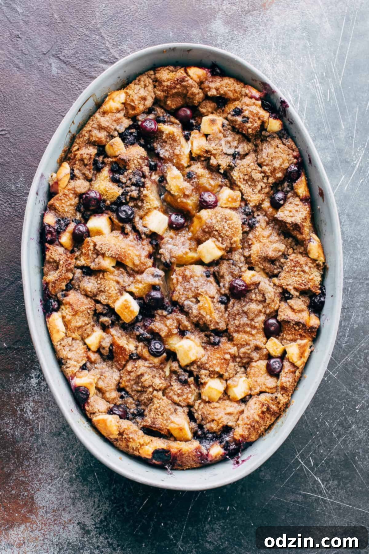 top shot of freshly baked dish with blueberry cheesecake French toast casserole on blue scratched surface