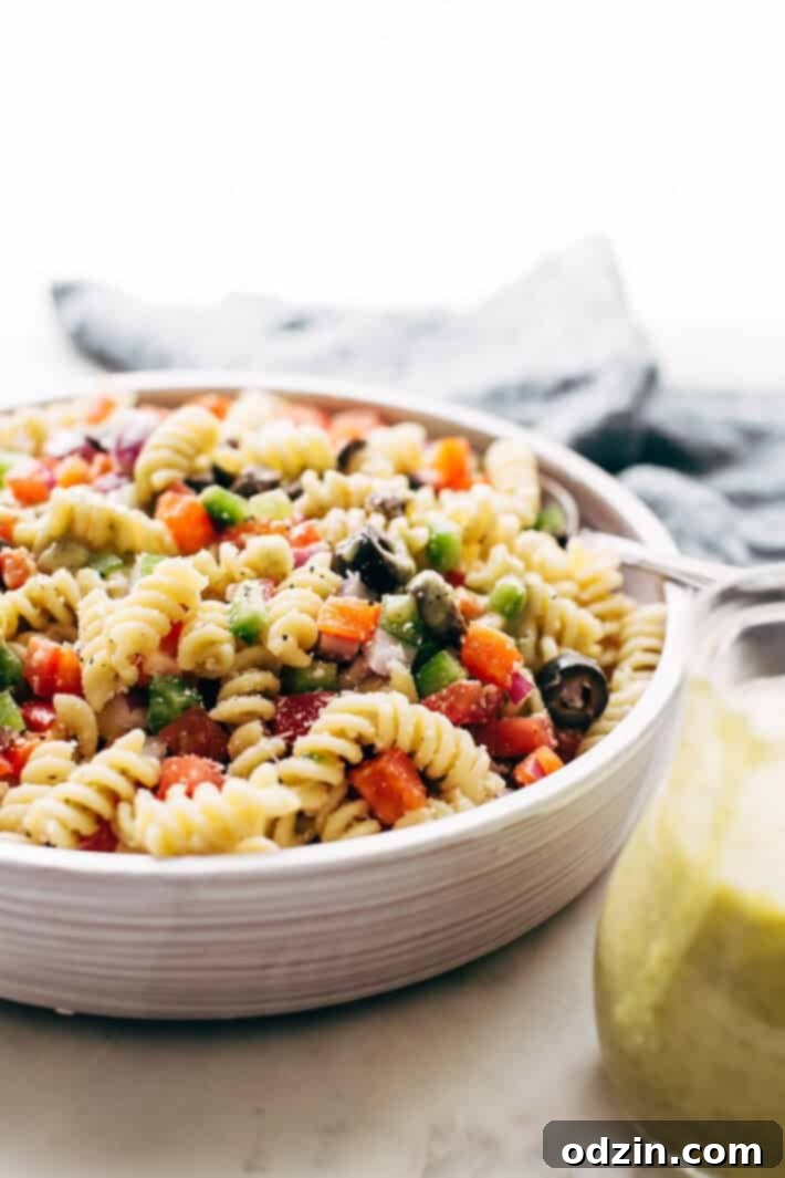 California Pasta Salad - made with homemade roasted garlic Italian dressing and tons of yummy salad toppings! Perfect for potlucks or picnics! #pastasalad #californiasalad #salad #spaghettisalad #potluck #choppedsalad | Littlespicejar.com Close-up of California Pasta Salad featuring perfectly cooked pasta, colorful bell peppers, black olives, and a light dressing. A great side dish or light meal.