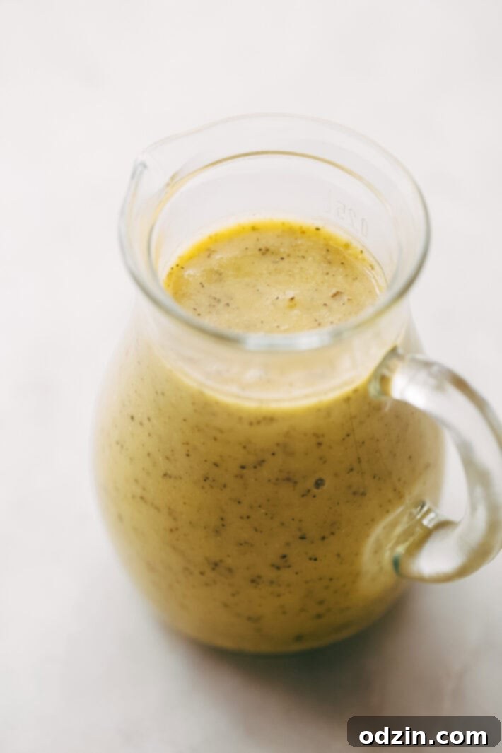 California Pasta Salad - made with homemade roasted garlic Italian dressing and tons of yummy salad toppings! Perfect for potlucks or picnics! #pastasalad #californiasalad #salad #spaghettisalad #potluck #choppedsalad | Littlespicejar.com A bowl of California Pasta Salad with a serving spoon, ready to be enjoyed. Features fresh, colorful ingredients.