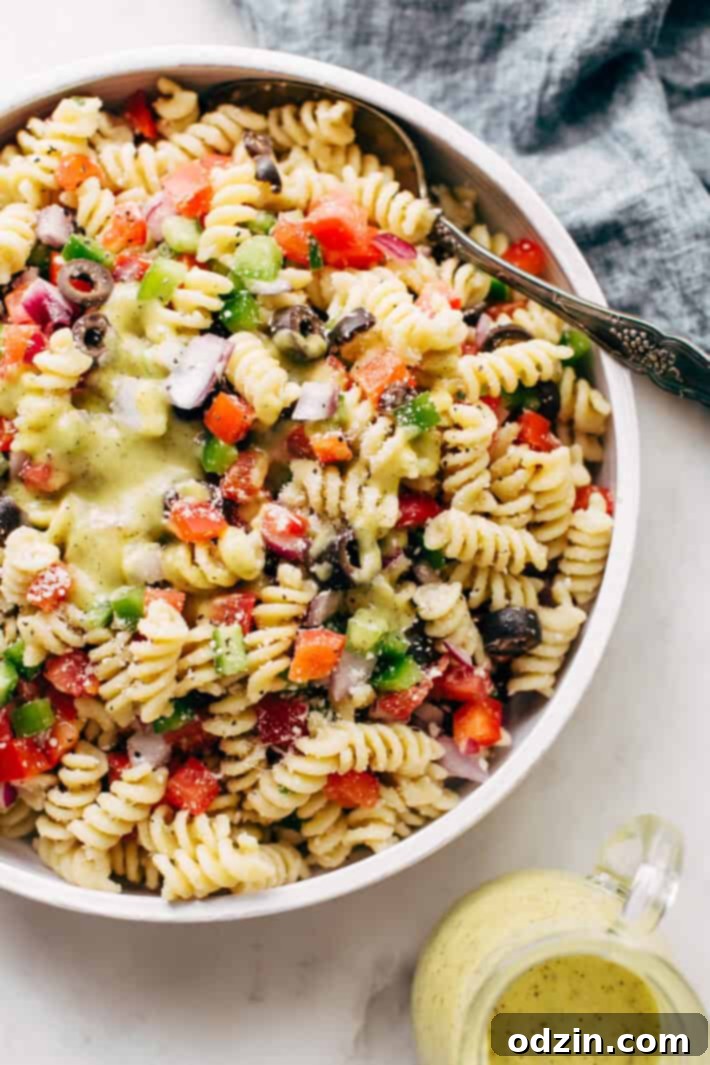 California Pasta Salad - made with homemade roasted garlic Italian dressing and tons of yummy salad toppings! Perfect for potlucks or picnics! #pastasalad #californiasalad #salad #spaghettisalad #potluck #choppedsalad | Littlespicejar.com A close-up of the homemade Roasted Garlic Italian Dressing being drizzled over the California Pasta Salad, showing its smooth consistency.