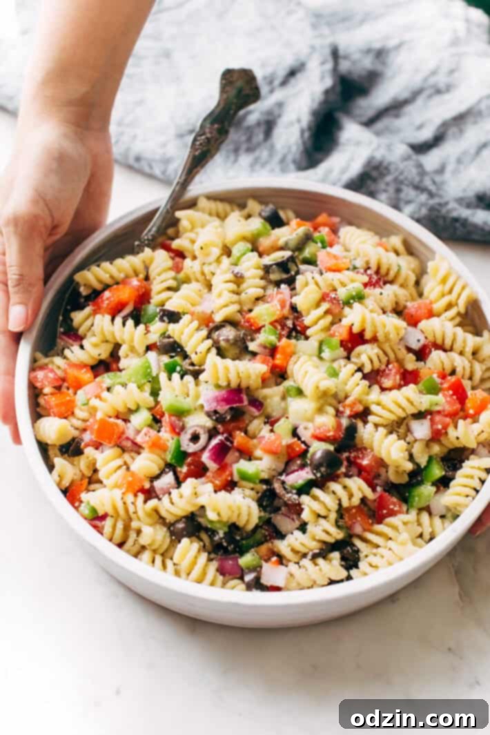 California Pasta Salad - made with homemade roasted garlic Italian dressing and tons of yummy salad toppings! Perfect for potlucks or picnics! #pastasalad #californiasalad #salad #spaghettisalad #potluck #choppedsalad | Littlespicejar.com California Pasta Salad displayed in a large serving bowl, ready to be enjoyed. Perfect for a refreshing summer meal.