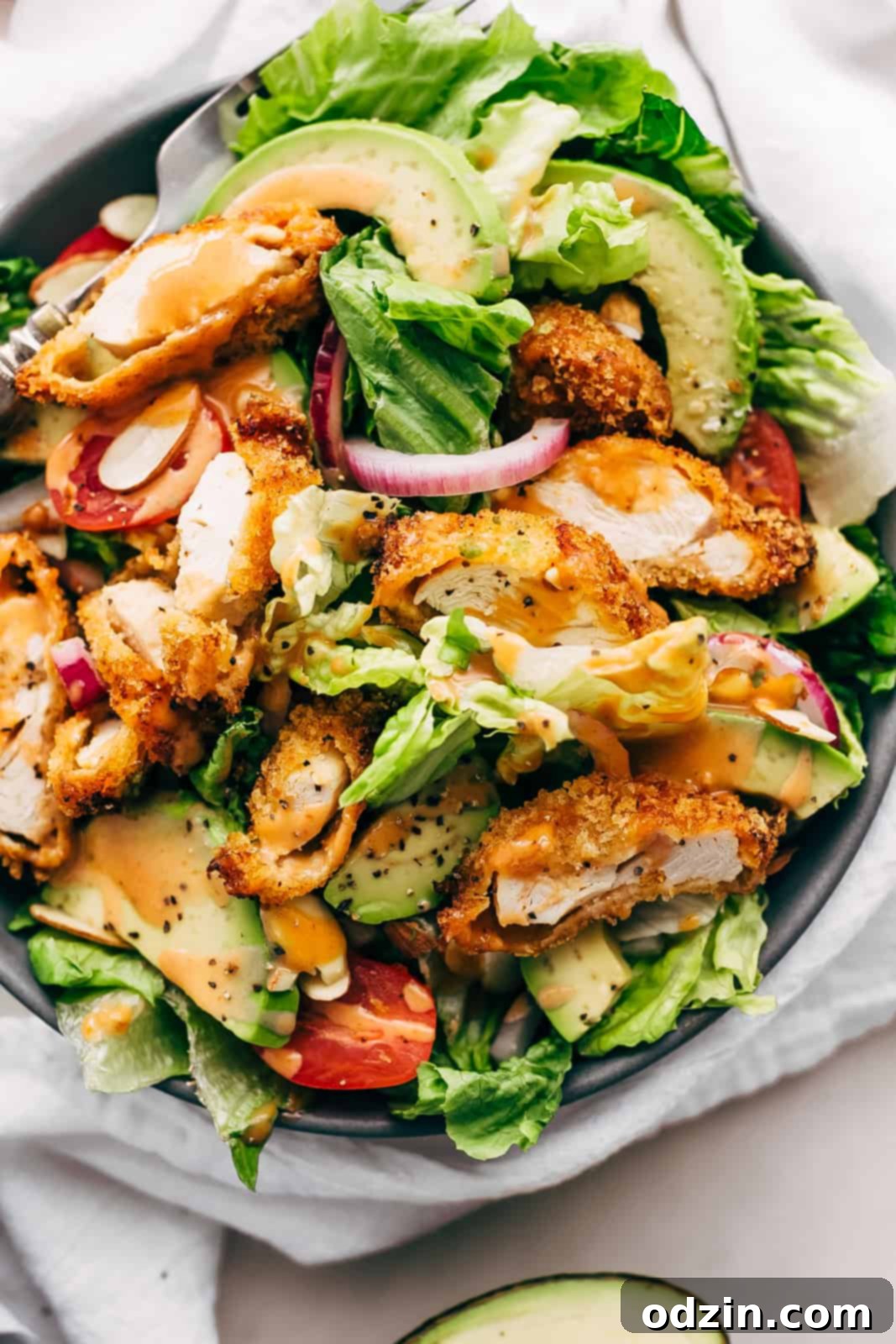 plate with salad topped with crispy chicken in strips dressed with creamy honey bbq dressing