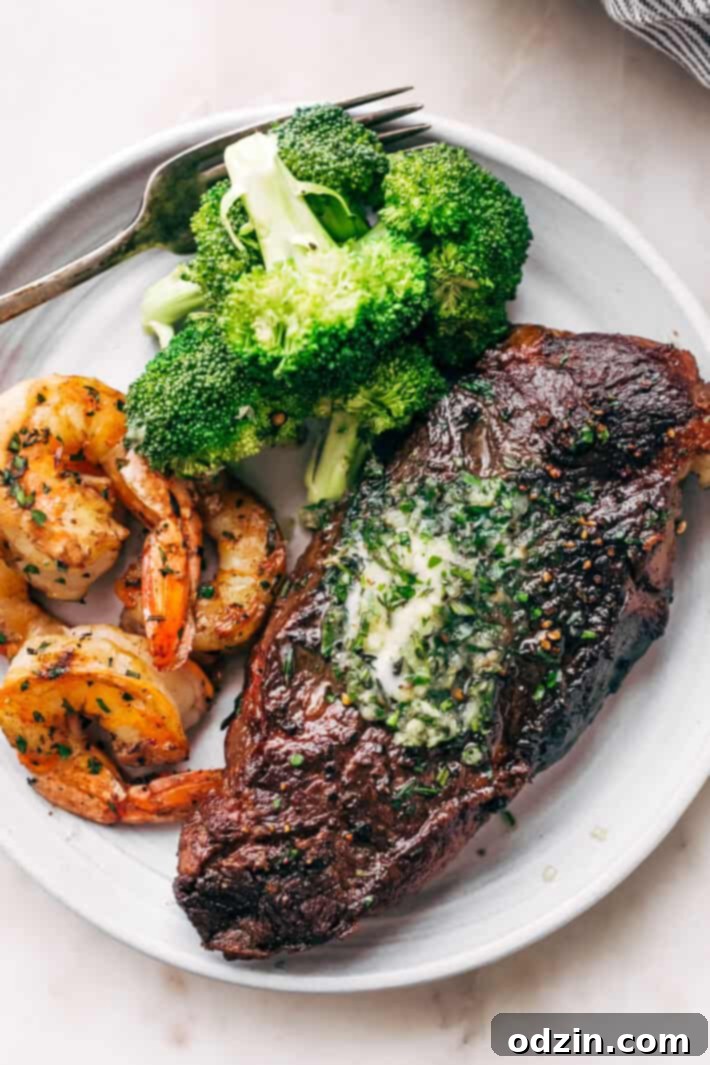 A close-up of the finished garlic butter skillet steak and shrimp, garnished with fresh rosemary, ready to be served.
