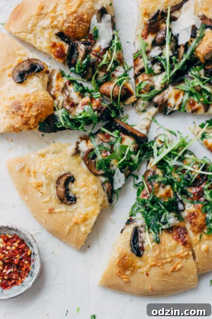 Hands preparing a Truffled Mushroom Pizza, spreading the garlic butter mushrooms and fresh mozzarella cheese on the dough infused with truffle oil. A step-by-step visual of this delicious homemade recipe.