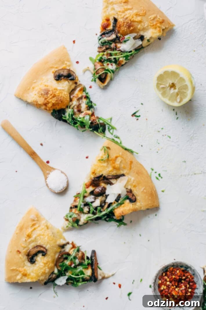 A perfectly baked Homemade Truffled Mushroom Pizza, sliced into generous portions and ready to serve, elegantly topped with a fresh arugula salad. This fancy pizza recipe is easy to make at home.