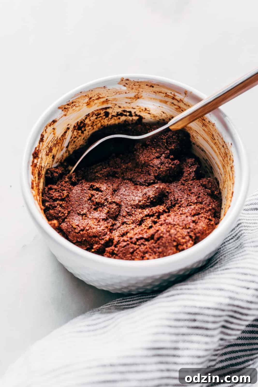 paste mixture for chili con carne in white bowl with spoon in white marble surface