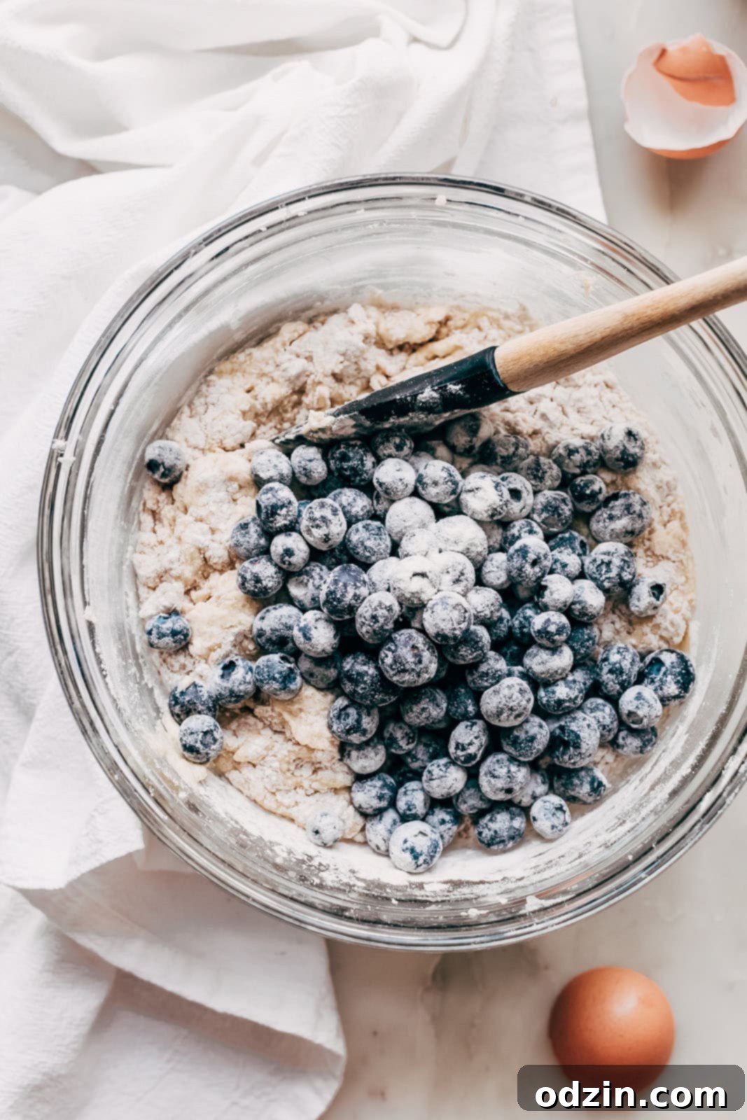 mixing bowl with blueberry muffin batter topped with floured fresh blueberries