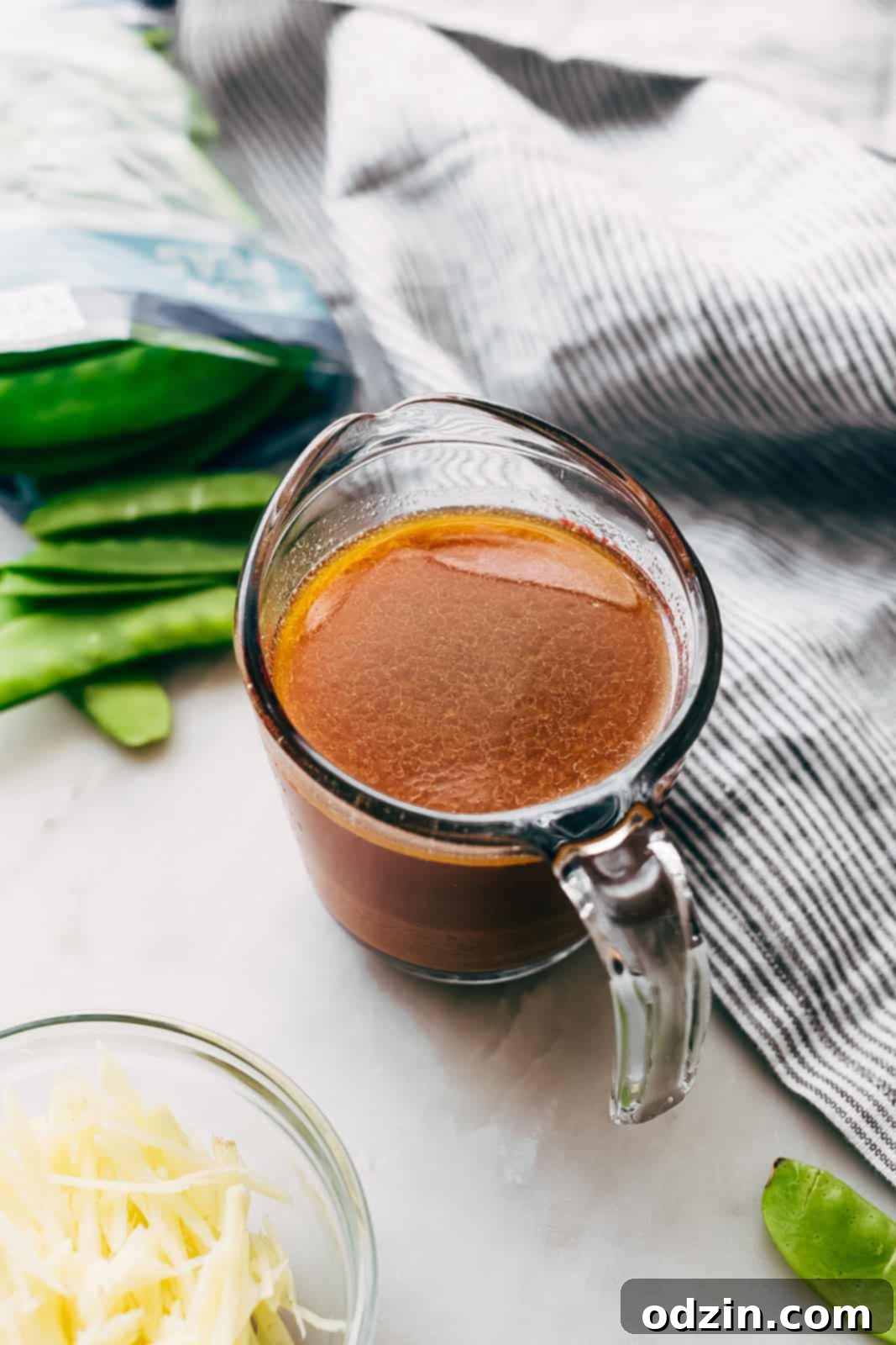 Speedy Ginger Shrimp and Snow Pea Stir Fry 5 prepared stir fry sauce in a measuring cup, surrounded by individual sauce ingredients on a marble surface