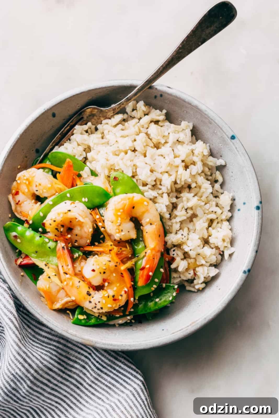 Speedy Ginger Shrimp and Snow Pea Stir Fry 8 brown rice with prepared stir fry in grey bowl speckled with blue dots, ready to eat