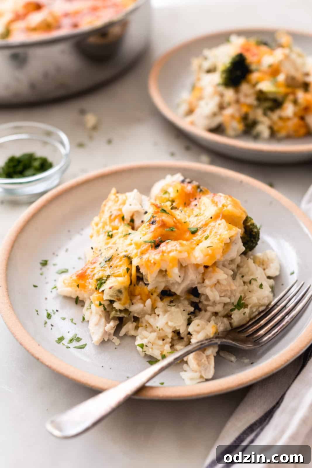 Easy One-Pot Cheesy Chicken, Broccoli & Rice Dinner 4 rice casserole on rimmed plates with fork on white marble