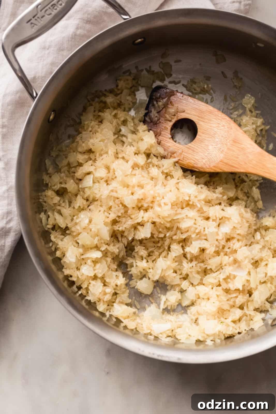 Easy One-Pot Cheesy Chicken, Broccoli & Rice Dinner 6 sautéed onions and rice with wooden spoon in pan