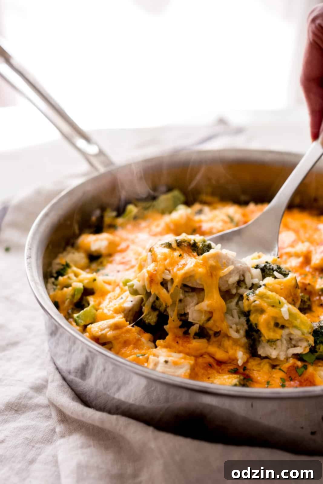 Easy One-Pot Cheesy Chicken, Broccoli & Rice Dinner 7 lifting a spoonful of casserole with melted cheese and broccoli showing