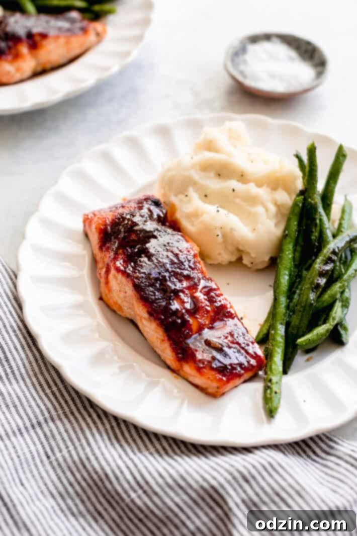 Prepared Spicy Maple Glazed Salmon with green beans and mashed potatoes on a fluted white plate, ready to serve.